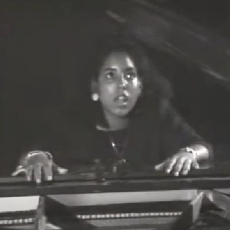 Danielle Chambers is singing, sitting behind the piano.